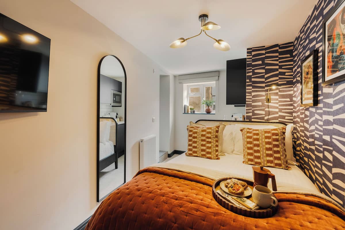 Un dormitorio moderno con una cama grande, un espejo, una pared con estampado de cebra y una zona de comedor con una bandeja de comida y una taza.
