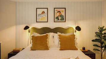 A neatly made bed with a quilted white cover, two brown pillows, and a tray with a bowl of fruit and a cup on the bed.