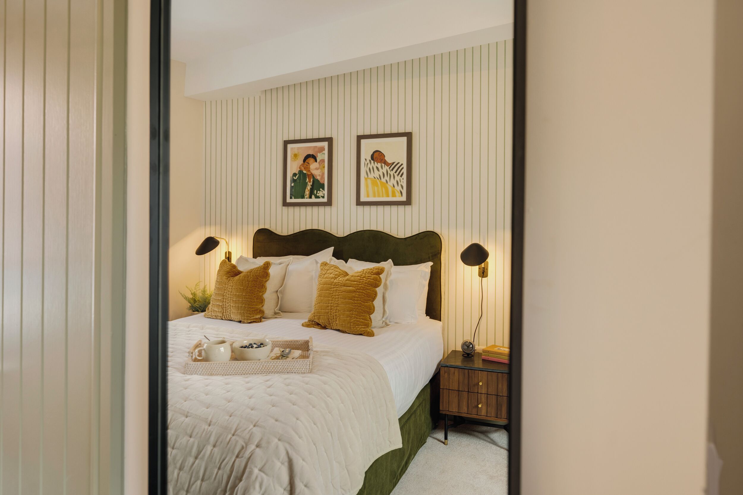 A neatly arranged bedroom with a bed, bedside tables, and wall art.