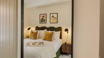 A neatly arranged bedroom with a bed, bedside tables, and wall art.