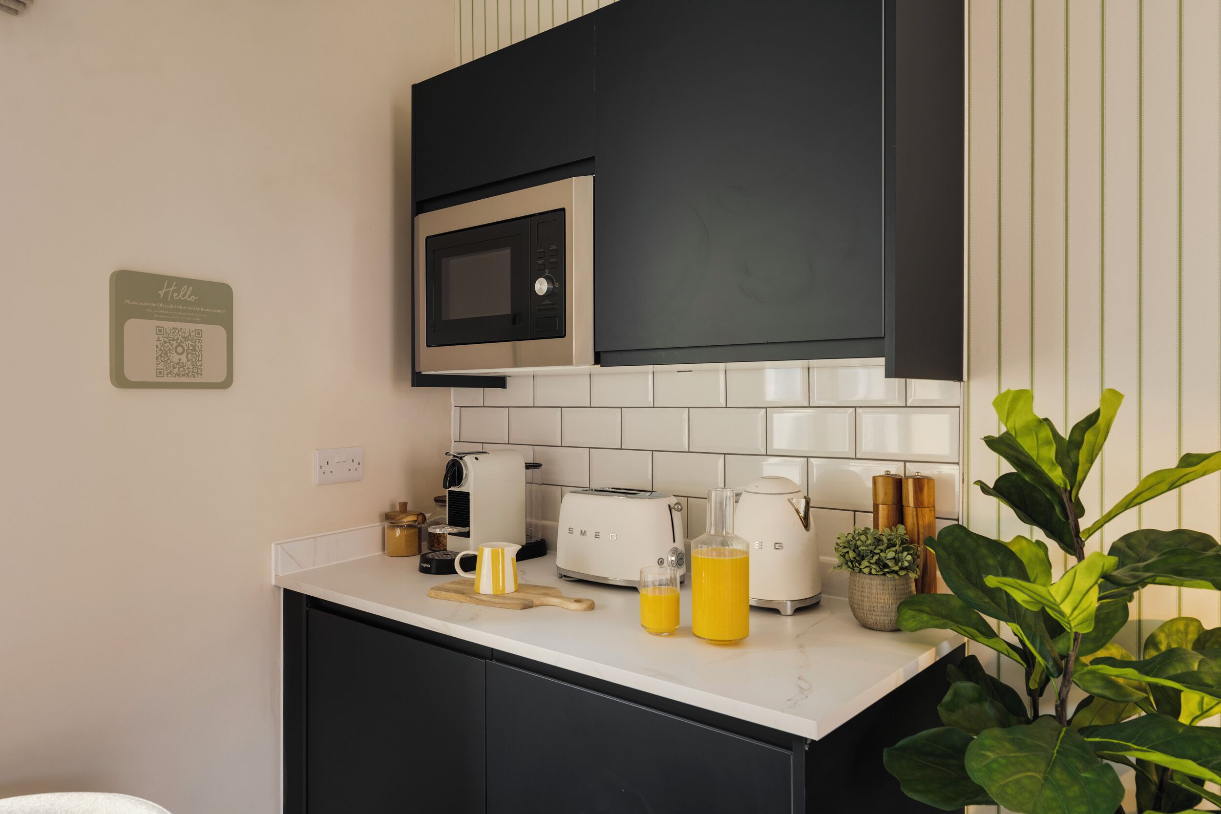 Cocina moderna con microondas, tostadora, hervidor y un código QR en la pared.