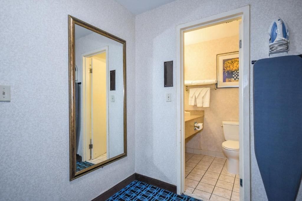 A bathroom with a large mirror, a toilet, a sink, and a shower area.
