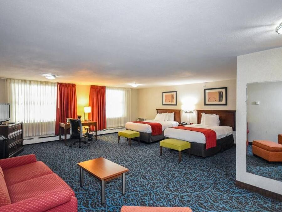 Une chambre d’hôtel avec deux lits, un bureau, une chaise, une télévision et un canapé.