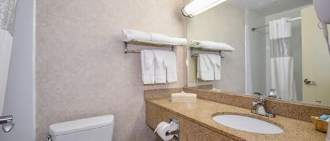 A bathroom with a toilet, sink, and mirror. There are towels on the wall and a hairdryer on the counter.