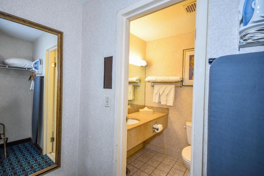 A compact hotel bathroom with a sink, toilet, and a mirror.