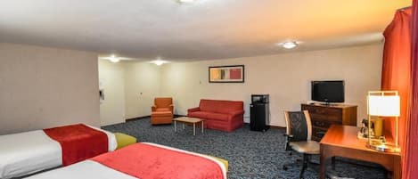 Habitación de hotel con dos camas, un escritorio con lámpara, televisión, una silla y una mesita.