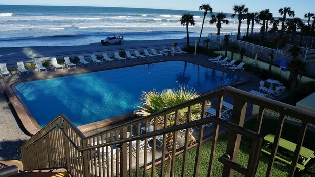 A pool with lounge chairs and a view of the ocean.