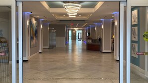 A hotel hallway with a modern design, featuring a reception desk, artwork on the walls, and a clear exit sign.