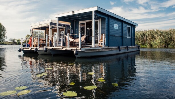 A houseboat with a covered deck, windows, and a dock. - Houseboat BunBo 1060 - Do (Königs Wusterhausen OT Zernsdorf)