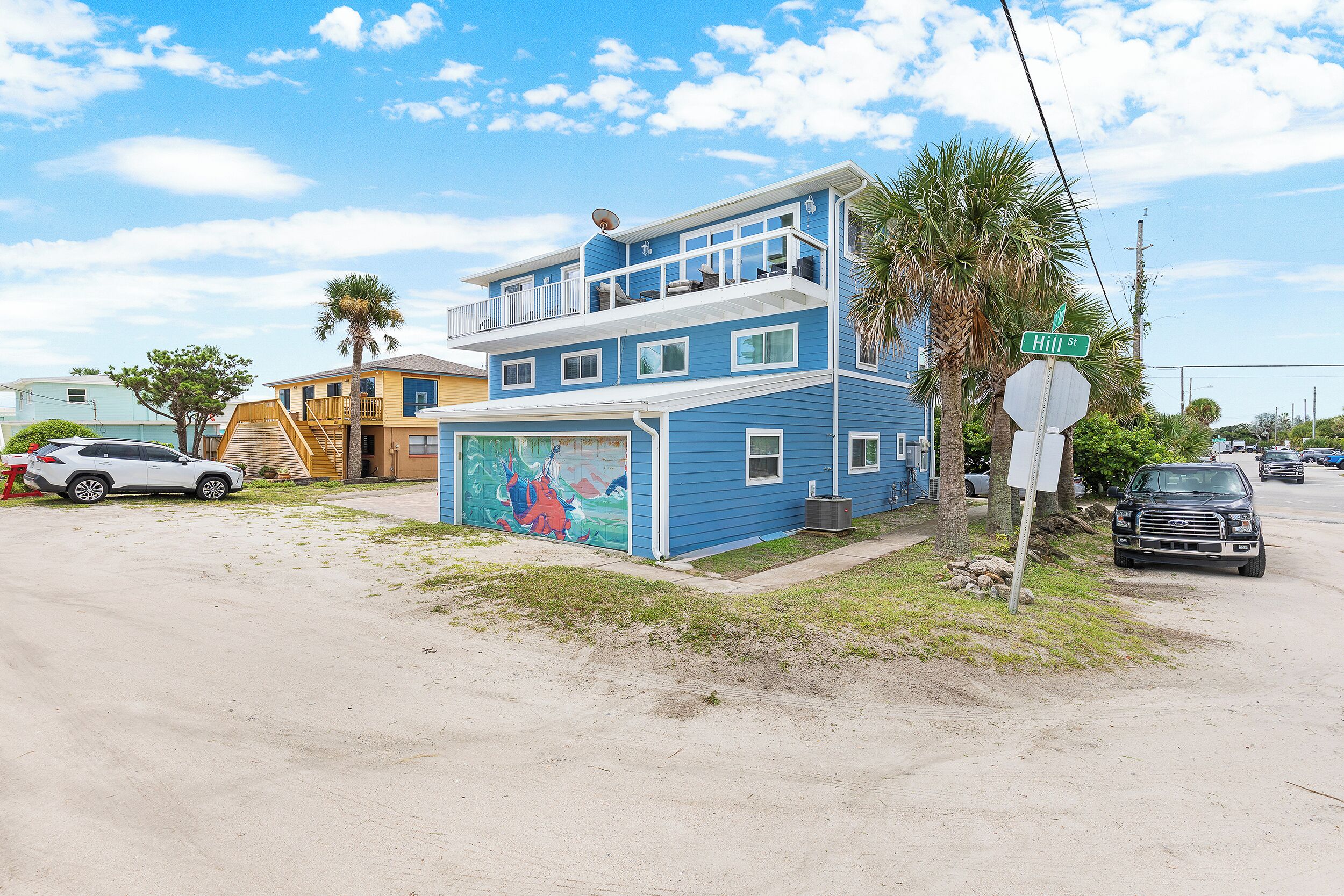 A two-story building with a blue exterior and a mural on the lower level.