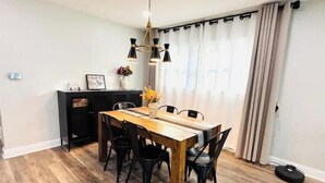 Un comedor con una mesa de madera y sillas negras, un armario negro y una araña.