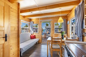 L’intérieur d’un chalet en bois comprend un canapé, une table à manger, des chaises et un coin cuisine.