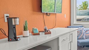 Une cuisine moderne équipée d’une machine à café, d’une plante en pot et d’un plateau contenant des ustensiles de cuisine.