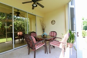 A covered patio with wicker furniture, a ceiling fan, and a glass door leading to a garden. - Walk out 2 bed 2 bath with shared pool, 10-15 mins to Marco beaches (Naples)