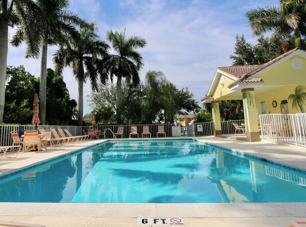 A swimming pool with lounge chairs and a no diving sign, surrounded by palm trees and a building with a tiled roof. - Walk out 2 bed 2 bath with shared pool, 10-15 mins to Marco beaches (Naples)
