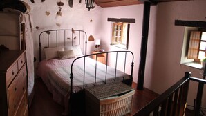 A bedroom with a single bed, wooden dresser, and a window with a view.