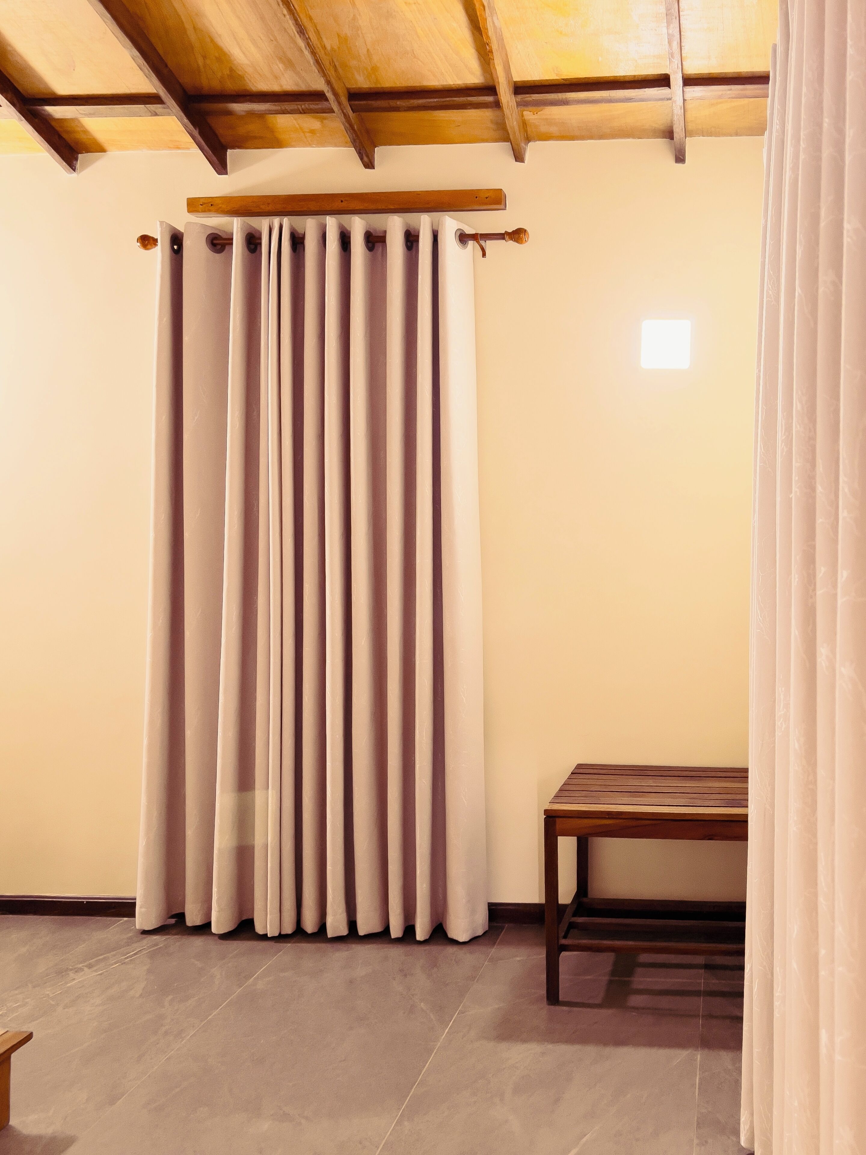 Una habitación con techo de madera, una ventana con vistas y un banco de madera.
