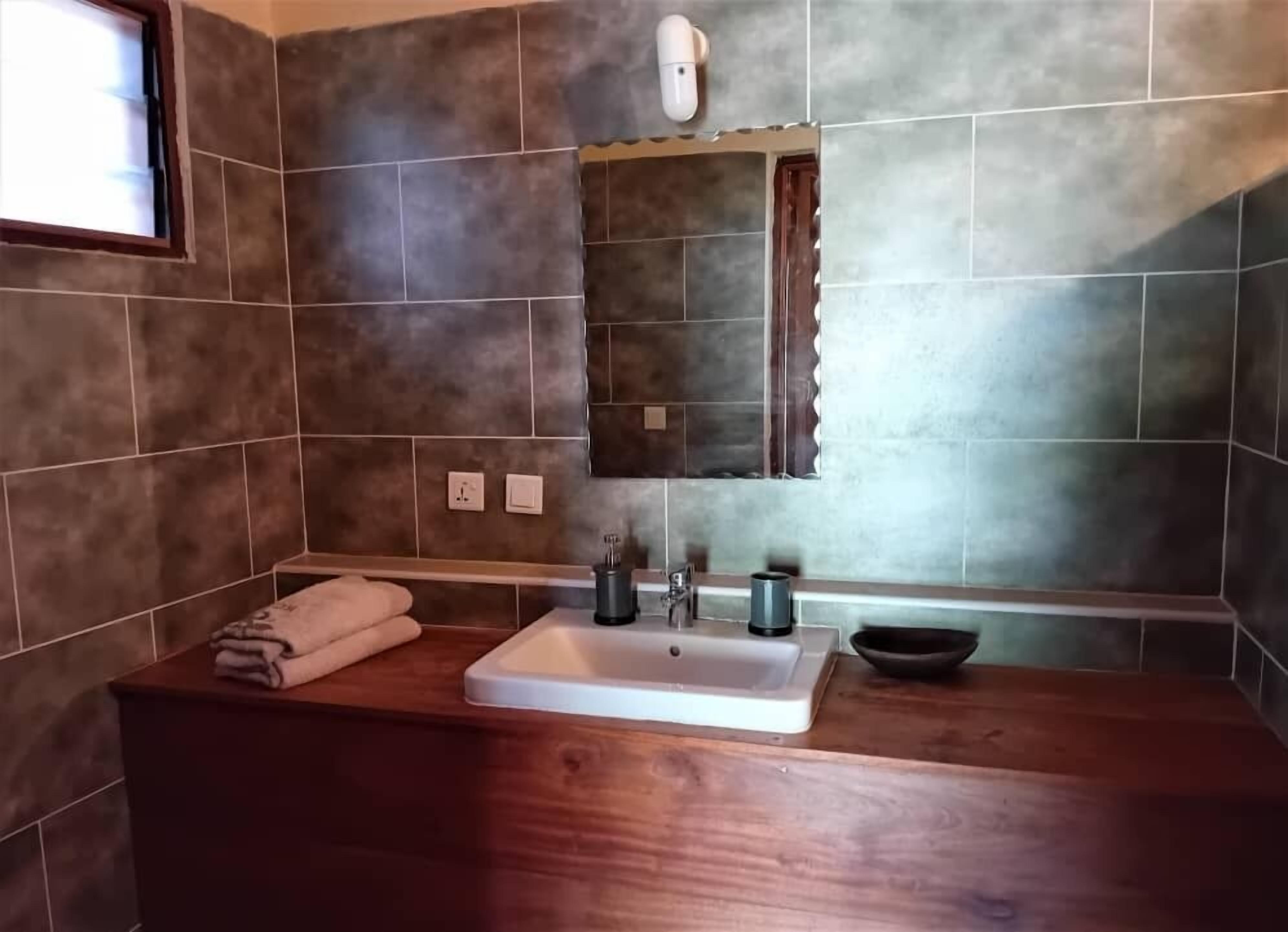 Un baño con tocador de madera, un lavabo, un espejo y una toalla sobre el mostrador.