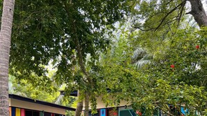 A colorful outdoor area with a stone pathway, a small seating area, and a building with vibrant murals. - Ko-Sa Beach Resort (Ampenyi)
