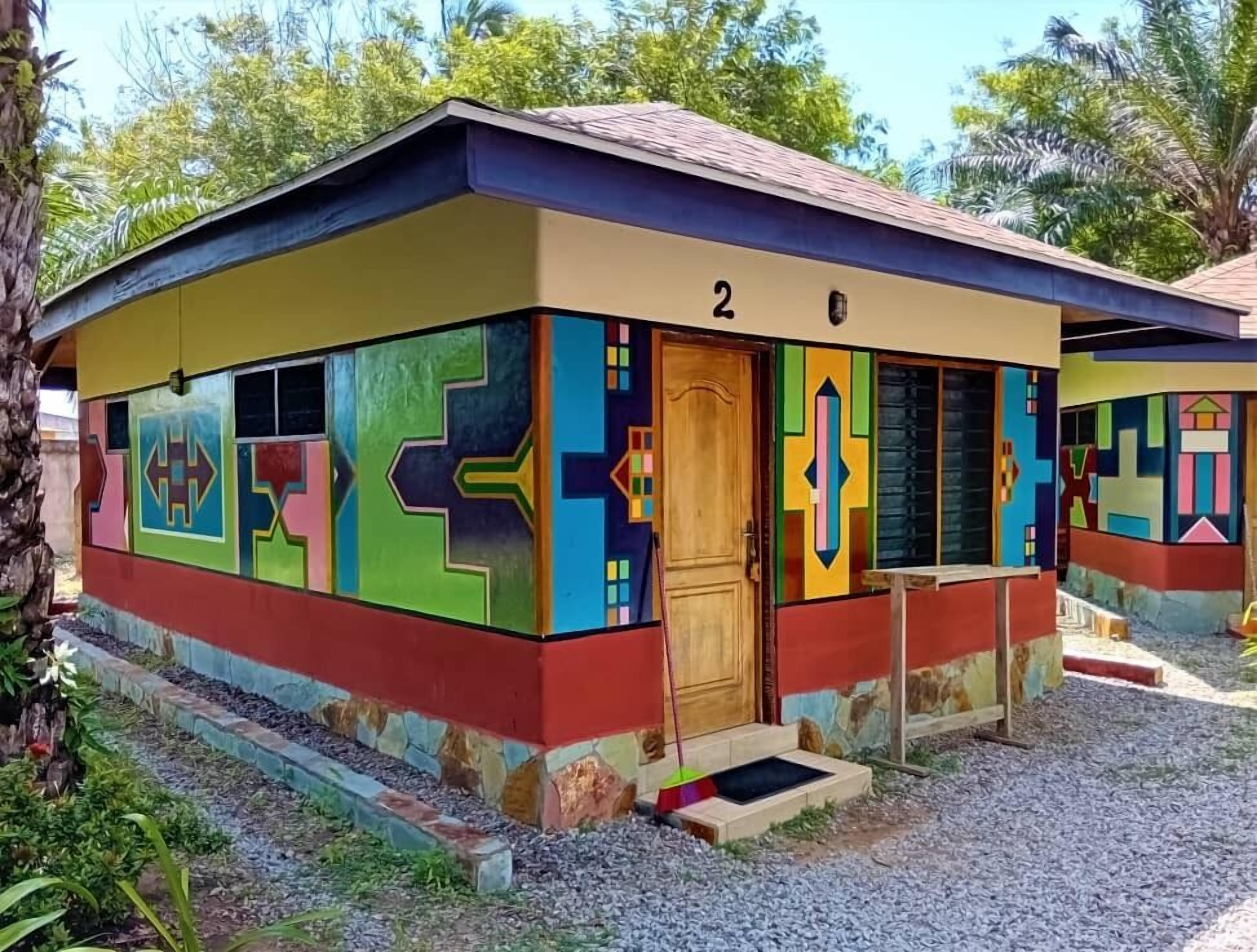 A small, colorful building with a number '2' on the side, a wooden door, and a small porch area.