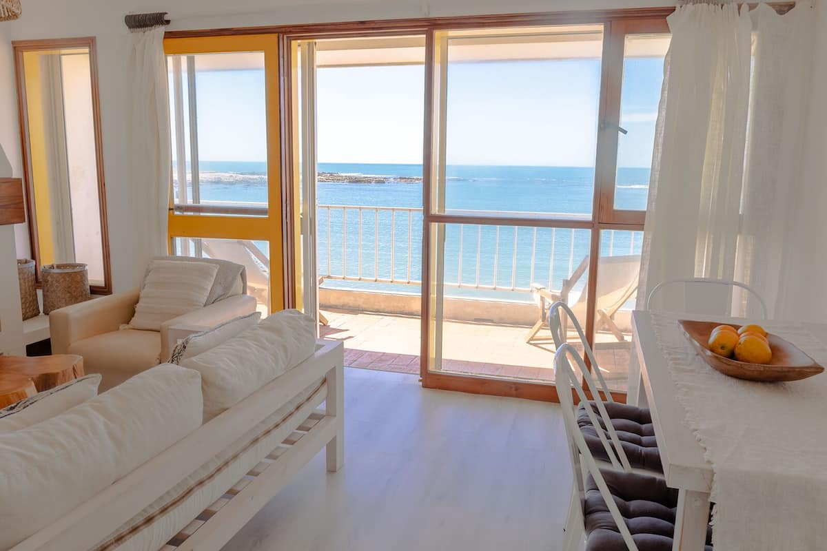 A spacious room with a large sliding glass door leading to a balcony overlooking the sea.