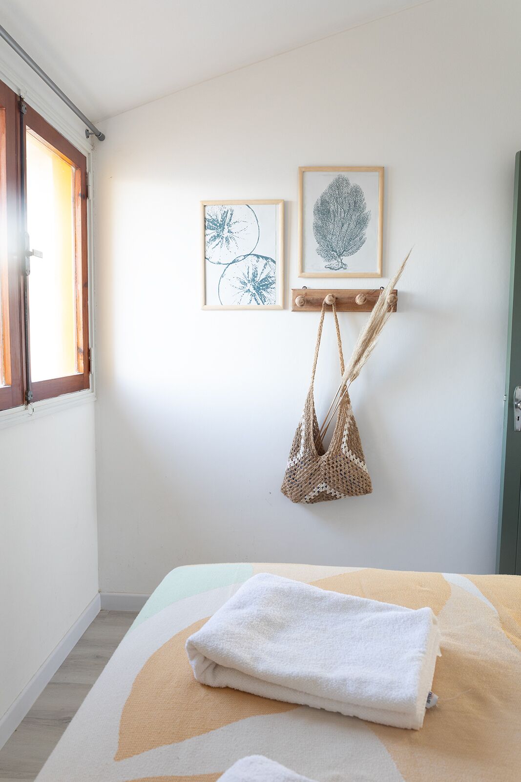 Un dormitorio con una cama, un bolso colgado y dos cuadros en la pared.