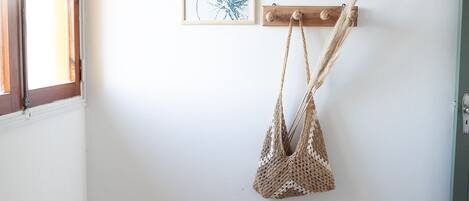 Un dormitorio con una cama, un bolso colgado y dos cuadros en la pared.