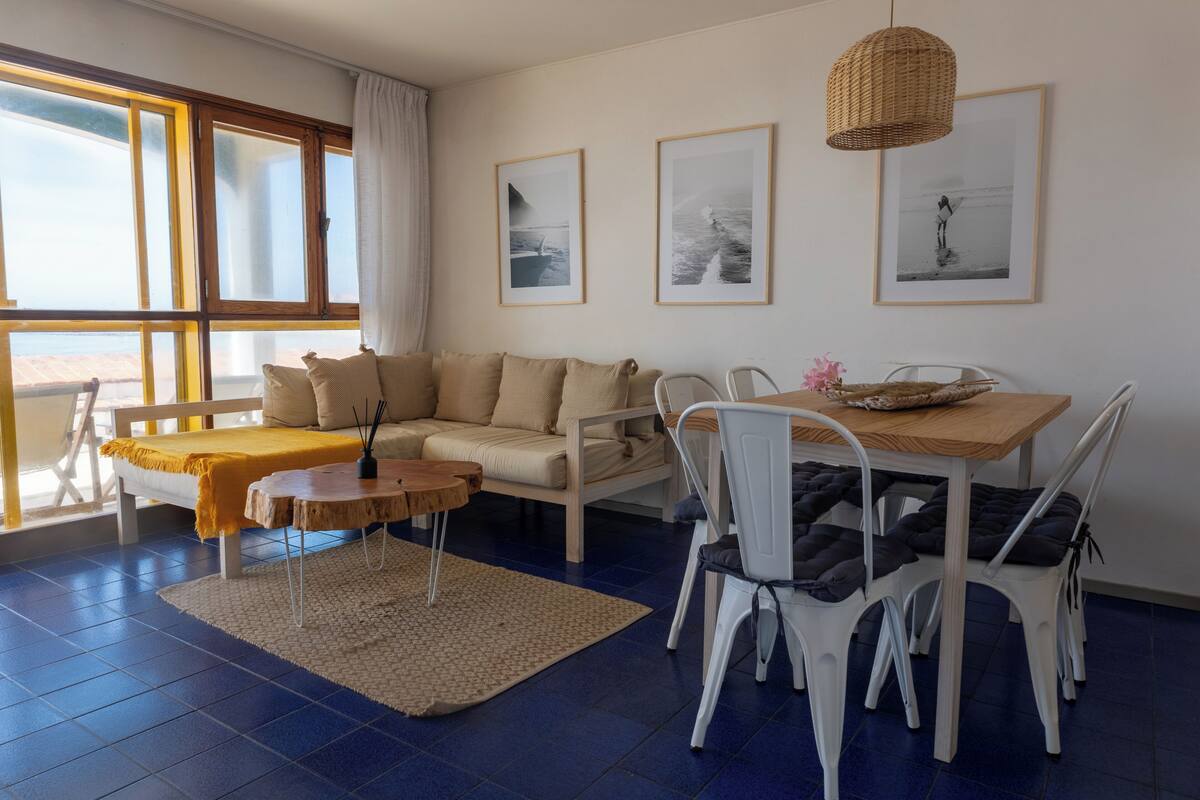 A modern living room with a sofa, dining table, chairs, and artwork on the walls.