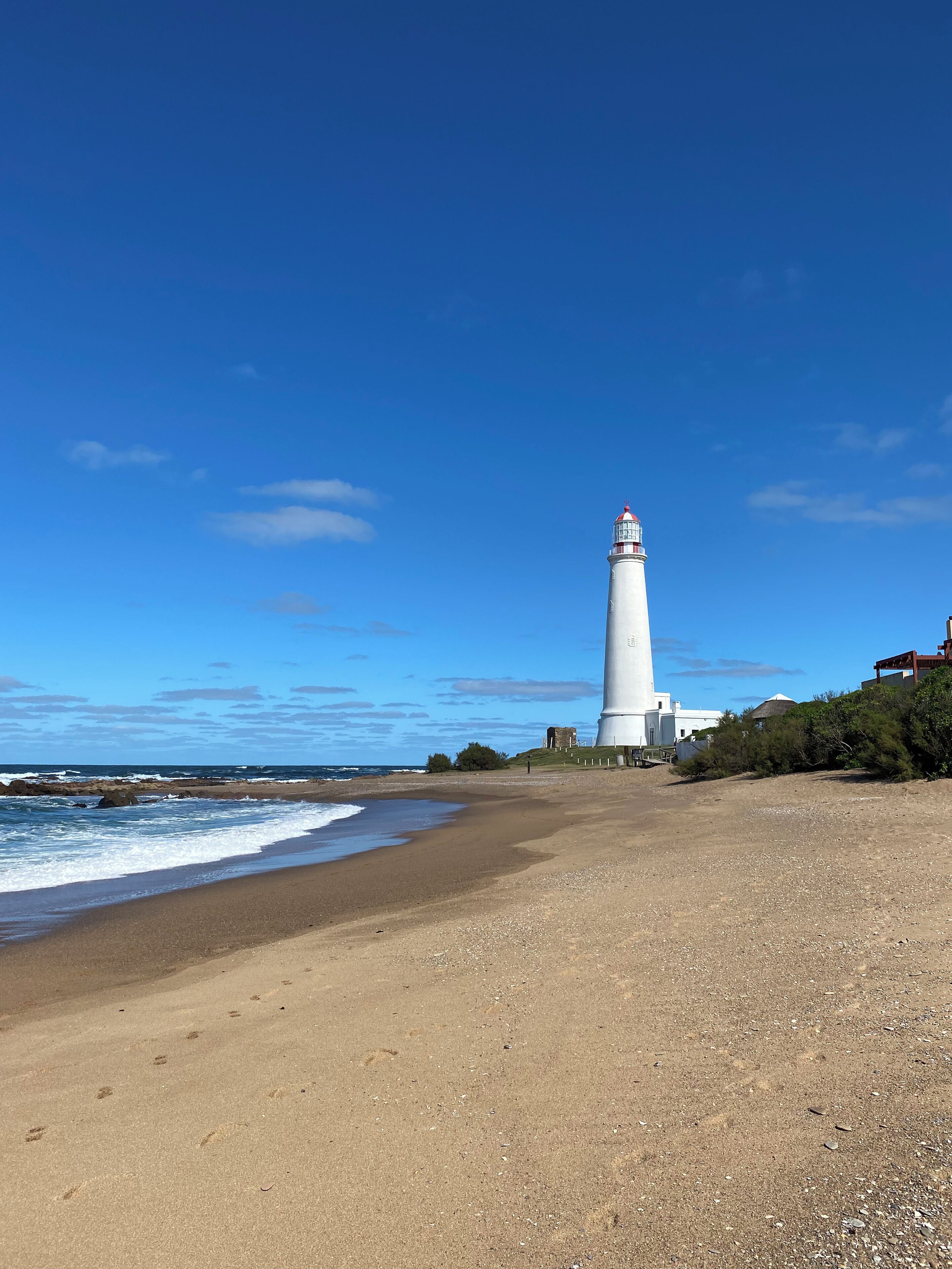 Un faro a la orilla del mar, bajo un cielo despejado.