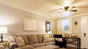 A living room with a sectional sofa, ottoman, and a ceiling fan.