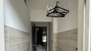 A narrow laundry room with a washing machine, a drying rack, and a mop. - Smart Lychee Studio Apartment #1 (Montería)