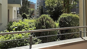 A view from a window of a building with a balcony, greenery, and other buildings in the background. - Three Bedroom Comfort Apartment Maintal (Maintal)