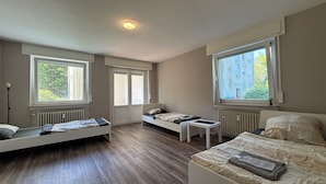 A room with two beds, a small table, and large windows. - Three Bedroom Comfort Apartment Maintal (Maintal)