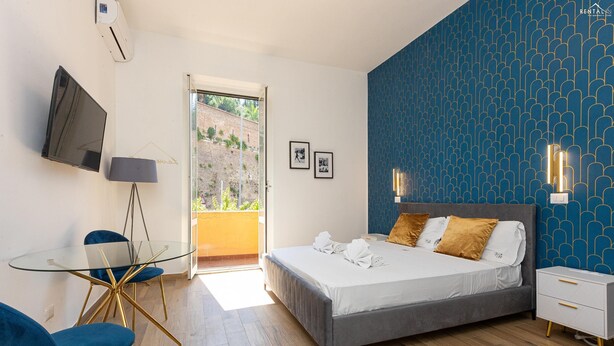 Une chambre moderne avec un lit, des tables de chevet, un téléviseur et une table en verre avec des chaises.