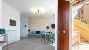A modern living room with a sofa, a dining table with chairs, and a ceiling light fixture. - Vatican Secret Apartment (Rome)