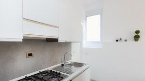 A modern kitchen with a gas stove, a sink, and a window providing natural light. - Vatican Secret Apartment (Rome)