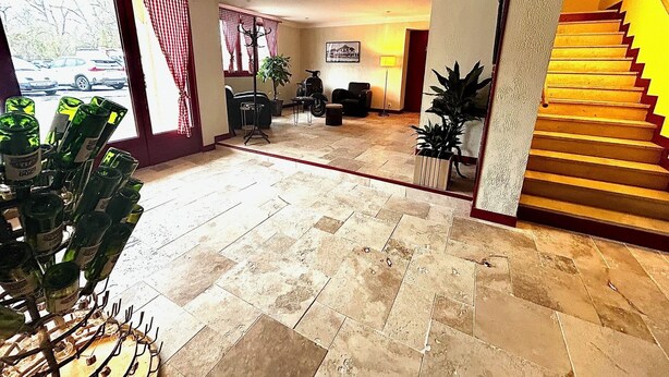 A hotel lobby with a tiled floor, a staircase, and a seating area with chairs and a table. - RELAIS LES 200 BORNES  (Pouilly-sur-Loire)