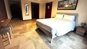 A bedroom with a bed, a desk, and a chair. There is a painting on the wall and a door with a sign. - RELAIS LES 200 BORNES  (Pouilly-sur-Loire)