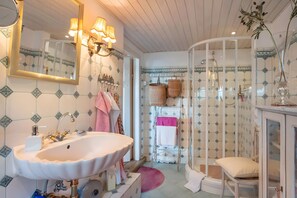 A bathroom with a white sink, mirror, and shower enclosure.