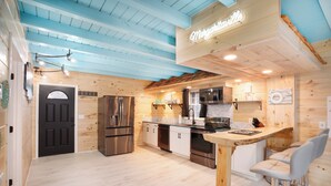 A modern kitchen with wooden walls, a black door, stainless steel appliances, and a bar area with two bar stools. - Margaritahills is the perfect getaway for  two couples, where rustic elegance meets modern comfort. (Creola)