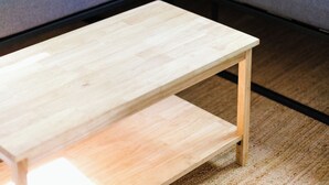 Una sala de estar moderna con un sofá seccional gris, una mesa de centro de madera y una alfombra pequeña.