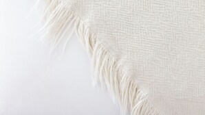 A close-up of a textured fabric with fringe details.