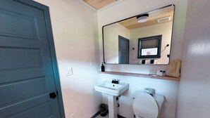 A bathroom with a white sink, toilet, and a mirror above the sink. - Amber Cottage at Piety Hill Cottages (NEVADA CITY)