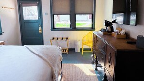 A bedroom with a bed, a dresser, a chair, and a window with a view of the outside.