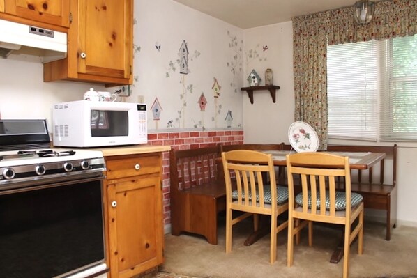 A kitchen with wooden cabinets, a microwave, a stove, and a dining table with chairs.