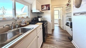 Une cuisine étroite avec une grande fenêtre, une cuisinière et un évier.