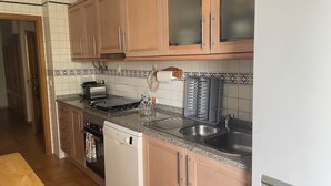 A kitchen with wooden cabinets, a toaster, a sink, and a dish rack.