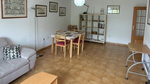 A spacious living area with a dining table, sofa, and a bookshelf.