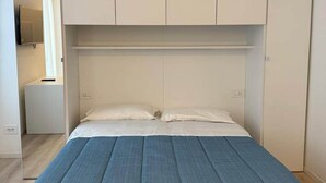 Un dormitorio con cama, armario y una mesita de noche.