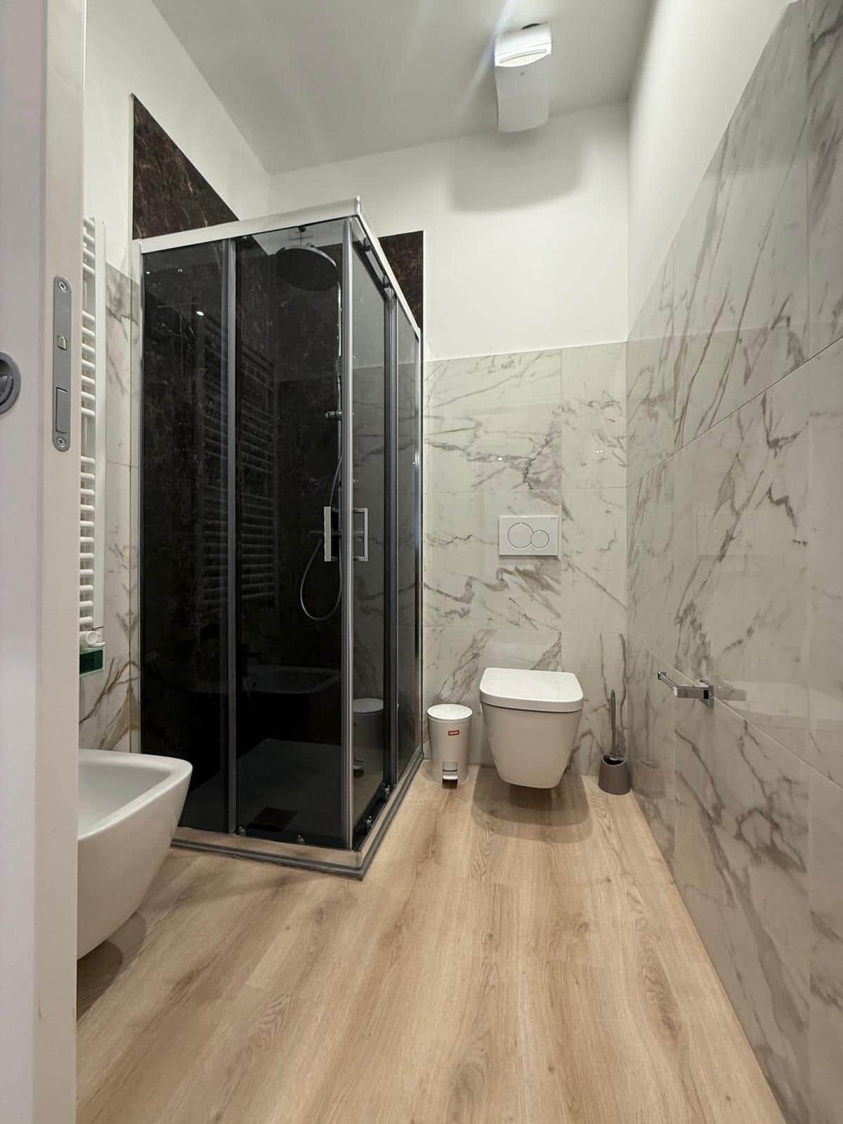 Un baño moderno con ducha envuelta en vidrio, inodoro y lavamanos.